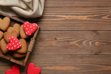 Lezzetli kalp şeklinde kurabiyeler ve ahşap arka planda masa örtüsü olan tepsi. Sevgililer Günü kutlaması