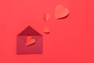 Zarflı kompozisyon ve kırmızı arka planda kağıt kalpler. Sevgililer Günü kutlaması