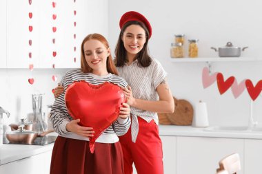 Sevgililer Günü 'nde mutfakta kalp şeklinde balonları olan genç lezbiyen çift.