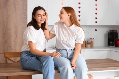 Sevgililer gününde mutfakta oturan genç lezbiyen çift