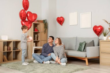 Küçük çocuk Sevgililer Günü 'nde ailesini hediye ve balonla karşılıyor.