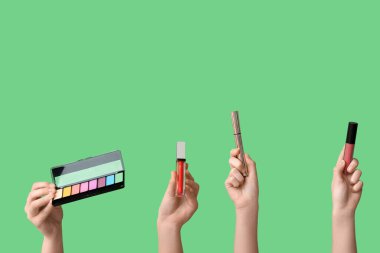 Göz falı, maskara ve yeşil arka planda ruj olan kadın elleri.