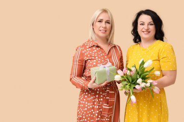 Bir buket güzel lalesi ve bej arka planda hediye kutusu olan olgun kadınlar. Uluslararası Kadınlar Günü