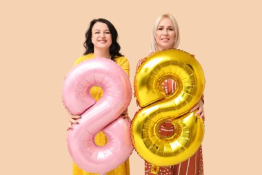 Bej arka planda 8 şeklinde balonları olan olgun kadınlar. Uluslararası Kadınlar Günü