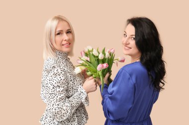 Bej arka planda bir buket güzel lalesi olan olgun kadınlar. Uluslararası Kadınlar Günü