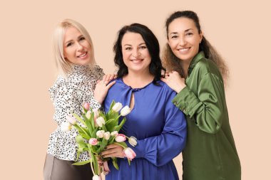 Bej arka planda güzel lalelerle dolu buketi olan mutlu olgun kadınlar. Uluslararası Kadınlar Günü