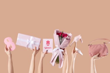 Bir buket lale, el çantası ve bej arka planda hediye kutusu olan kadın elleri. Uluslararası Kadınlar Günü için Alışveriş