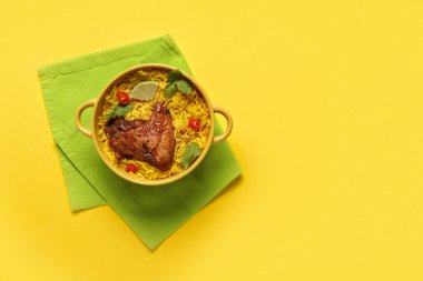 Sarı arka planda bir kase geleneksel tavuk biryani.