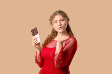 Tatlı çikolatalı güzel bir kadın kahverengi arka planda öpüşüyor.