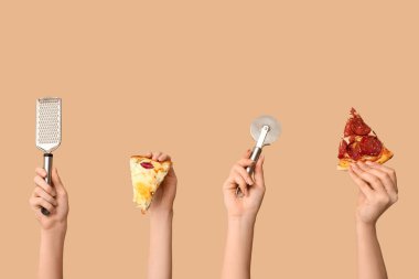 Birçok el bej arka planda pizza dilimleri, rende ve pizza kesicisi tutuyor.