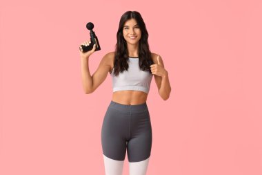 Pembe arka planda vurmalı masaj aleti olan genç bir kadın.