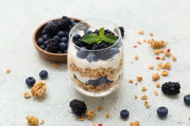 Hafif arka planda yoğurtlu bir bardak lezzetli granola, yakın plan.