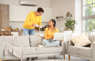 Mutfakta dizüstü bilgisayar kullanan kahve içen genç bir çift.