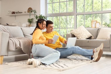 Evde dizüstü bilgisayar ve tablet bilgisayar kullanan genç bir çift