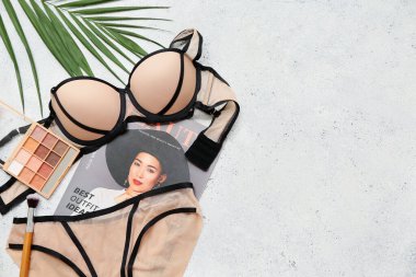 Şık kadın iç çamaşırları, göz farı, dergi ve arka planda palmiye yaprağı olan kompozisyon