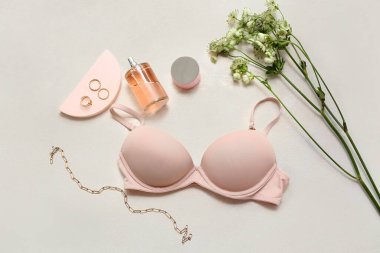 Kadın sütyeni, aksesuar, parfüm ve çiçekli kompozisyon