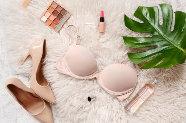 Kadın sütyeni, ayakkabı ve kozmetik ürünleriyle hafif kabarık halı üzerinde kompozisyon