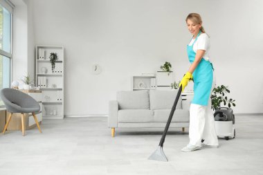Kadın temizlikçi. Ofiste yerleri süpürüyor.