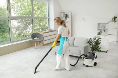 Kadın temizlikçi. Ofiste yerleri süpürüyor.