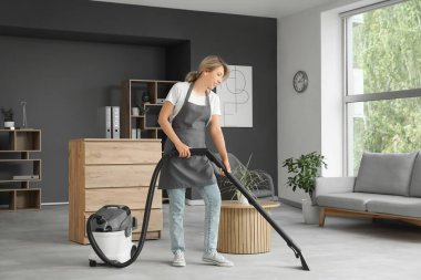 Kadın temizlikçi. Ofiste yerleri süpürüyor.