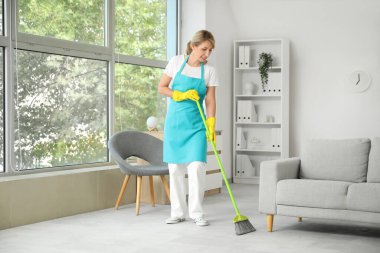 Kadın hademe ofisi temizliyor.