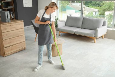 Kadın hademe ofisi temizliyor.