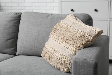 Oturma odasında yumuşak yastıklı gri kanepe, yakın çekim.