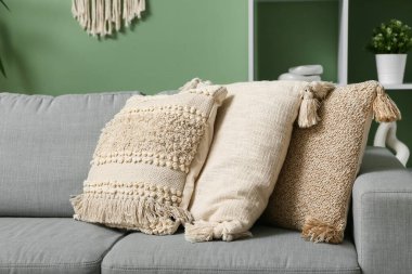 Şık oturma odasında yumuşak yastıklı gri kanepe.