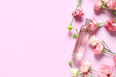 Bir şişe parfüm ve pembe arka planda Eustoma çiçekleri.