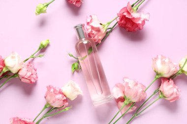 Bir şişe parfüm ve pembe arka planda Eustoma çiçekleri.