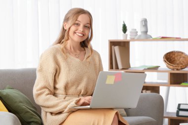 Ofisteki kanepede dizüstü bilgisayarla çalışan kadın web tasarımcısı.