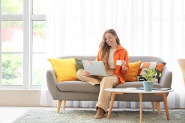 Ofisteki koltukta oturan dizüstü bilgisayarı ve kahve fincanı olan kadın web tasarımcısı.