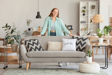 Mutfaktaki kanepenin arkasında genç bir kadın var.