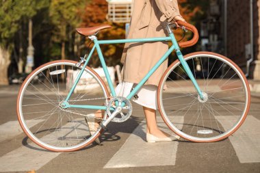 Bisikletli genç bir kadın yaya geçidinden geçiyor.