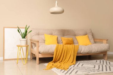 Konforlu kanepe, çiçek, çerçeve ve sallanan lamba oturma odasının içinde.