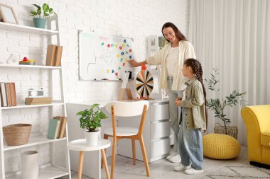 Ofiste beyaz tahtanın yanında küçük bir kızla çalışan kadın konuşma terapisti.