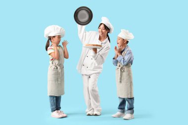 Lezzetli turtası olan Asyalı kadın şef ve mavi arka planda küçük çocukları.