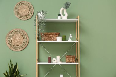 Raflarda yanan mumlar ve yeşil duvarın yanındaki bitkiler.