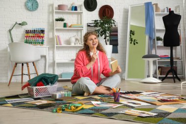 Stüdyoda halıyla uğraşan düşünceli kadın moda tasarımcısı.