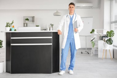 Kliniğin resepsiyonunda panosu olan bir erkek stajyer.