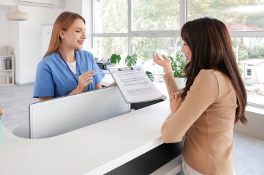 Klinikteki resepsiyondaki hastaya form veren kadın stajyer.