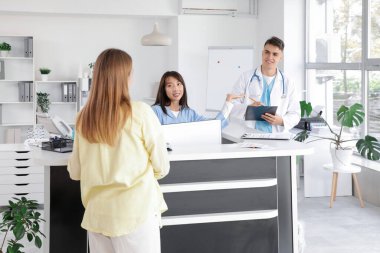 Klinikte hasta ve doktorla çalışan bir stajyer.