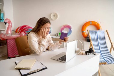 Pasaportu olan düşünceli bir iş kadını yaz tatilini ofisinde bekliyor.