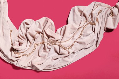 Pembe arka planda farklı altın kolyeler.