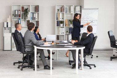 Çizelgeye yakın bayan avukat ve ofiste çalışan meslektaşlar.