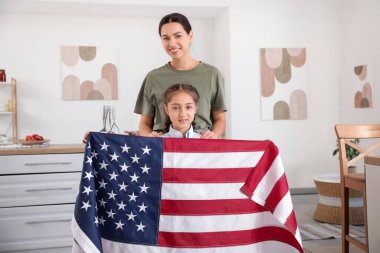 Kadın asker ve kızı mutfakta Amerikan bayrağı taşıyorlar.