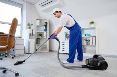 Temizlikçi ofiste yerleri süpürüyor.