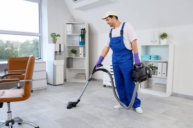 Temizlikçi ofiste yerleri süpürüyor.