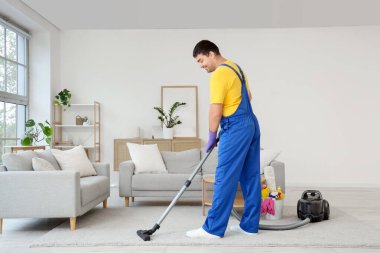 Kapıcı odada halı süpürüyor.