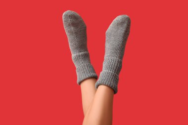 Kırmızı arka planda gri örgülü çoraplı genç kadın bacakları.